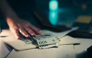 Australian compensation payment: Hand reaches for $3,000 scam victim payout on office desk.