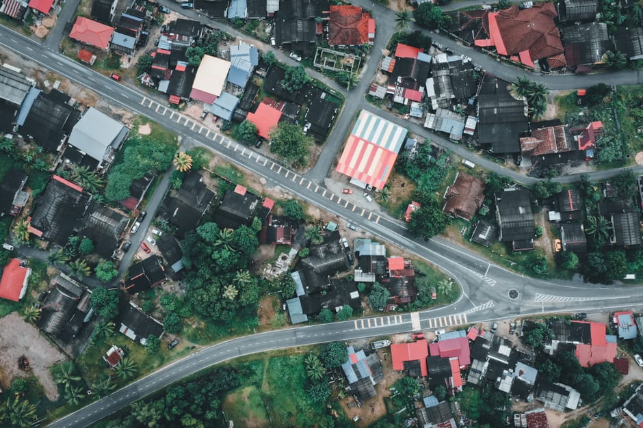 Sunshine Coast housing development high-angle shot, vibrant rooftops, green Malaysia.