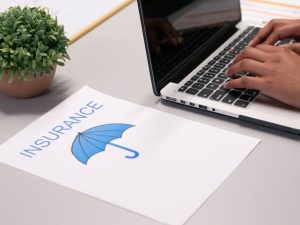 Insurance claim: Hands type on laptop near luxury car dealership heist insurance document, Australia.
