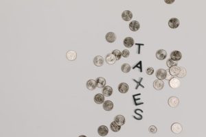 Scattered coins forming the word 'TAXES' on a white surface, symbolizing financial concepts.