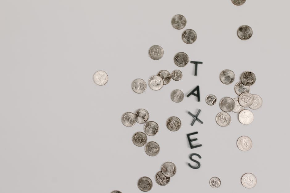 Scattered coins forming the word 'TAXES' on a white surface, symbolizing financial concepts.